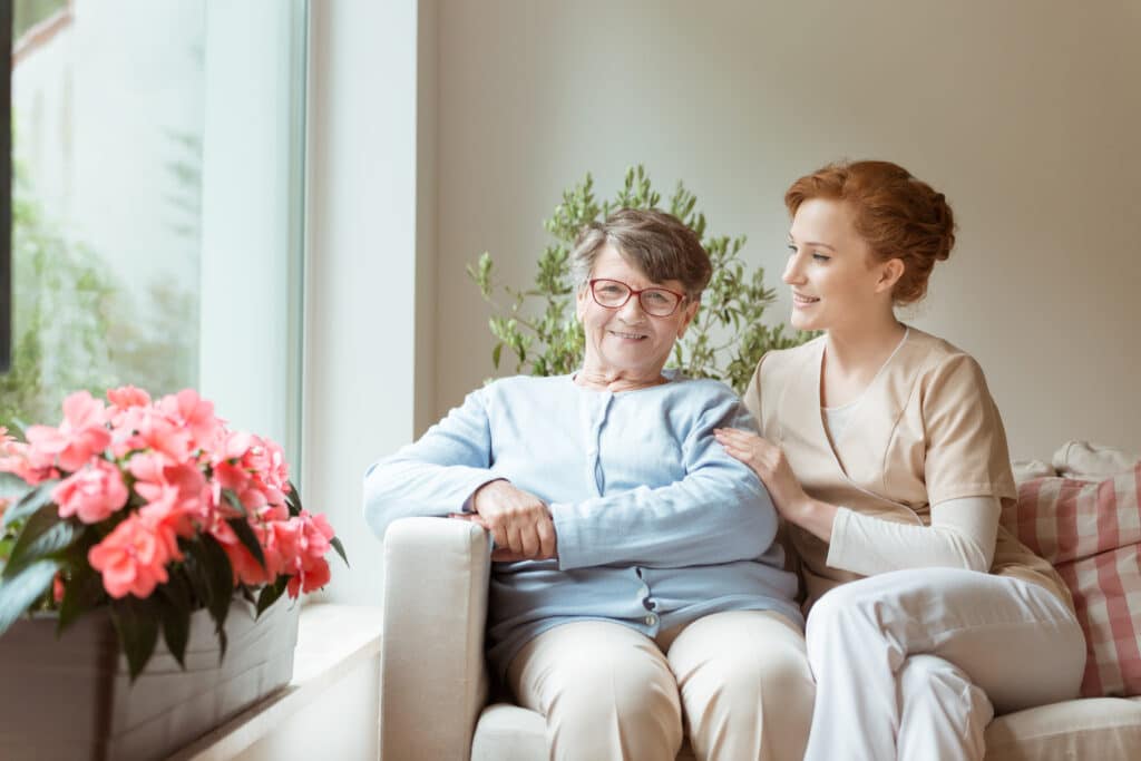 A man and woman sitting in a chair next to flowers.