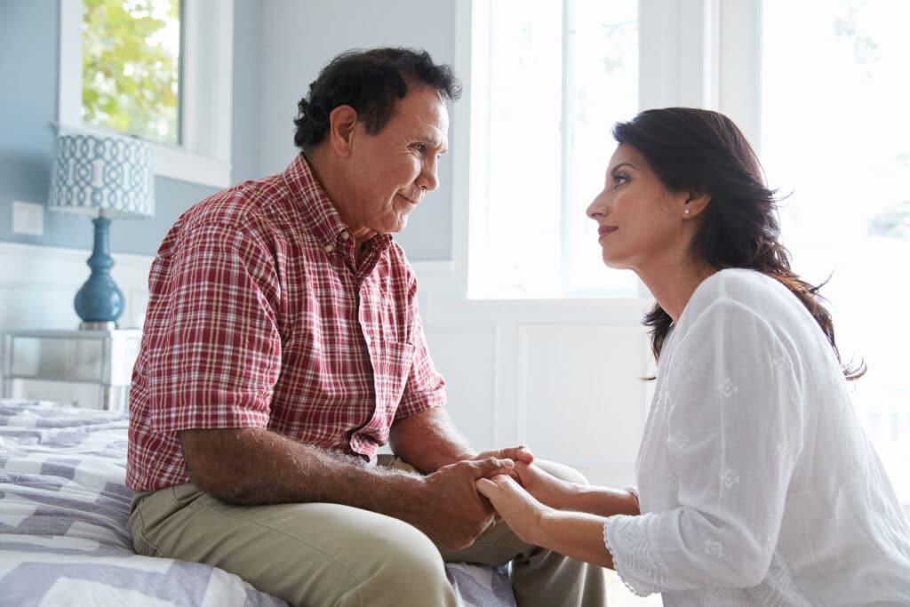 A man and woman sitting on the couch talking.