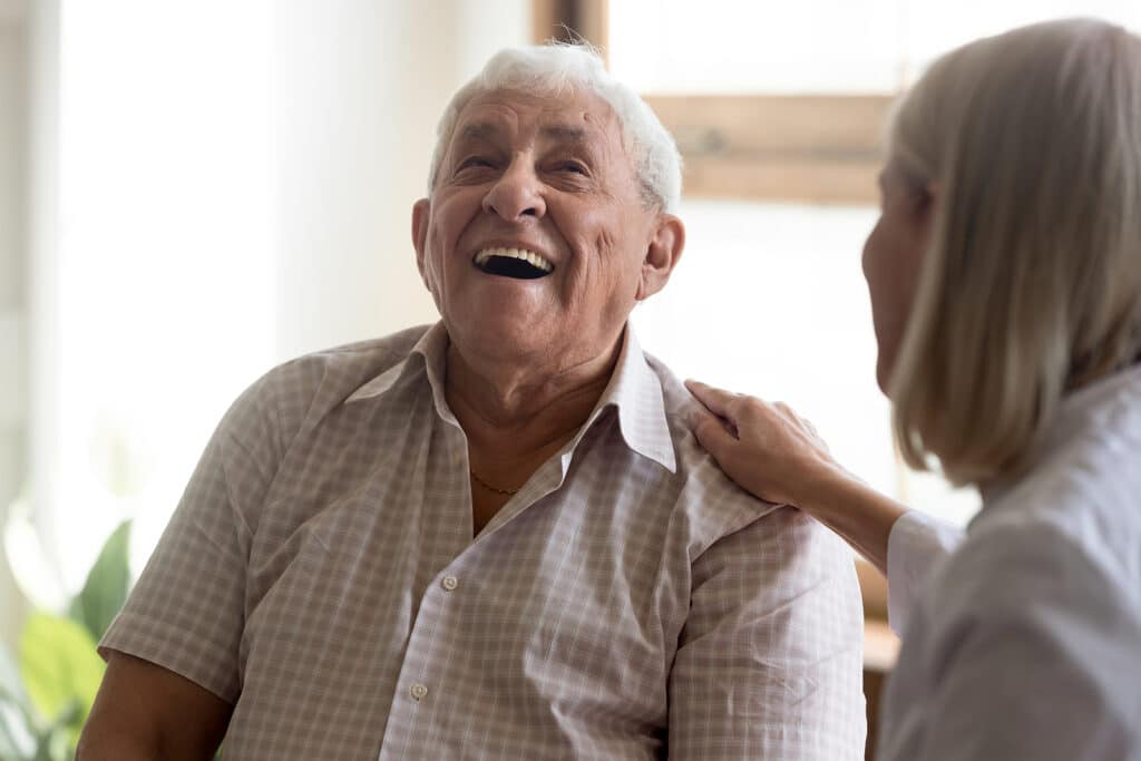 A woman is helping an older man laugh.