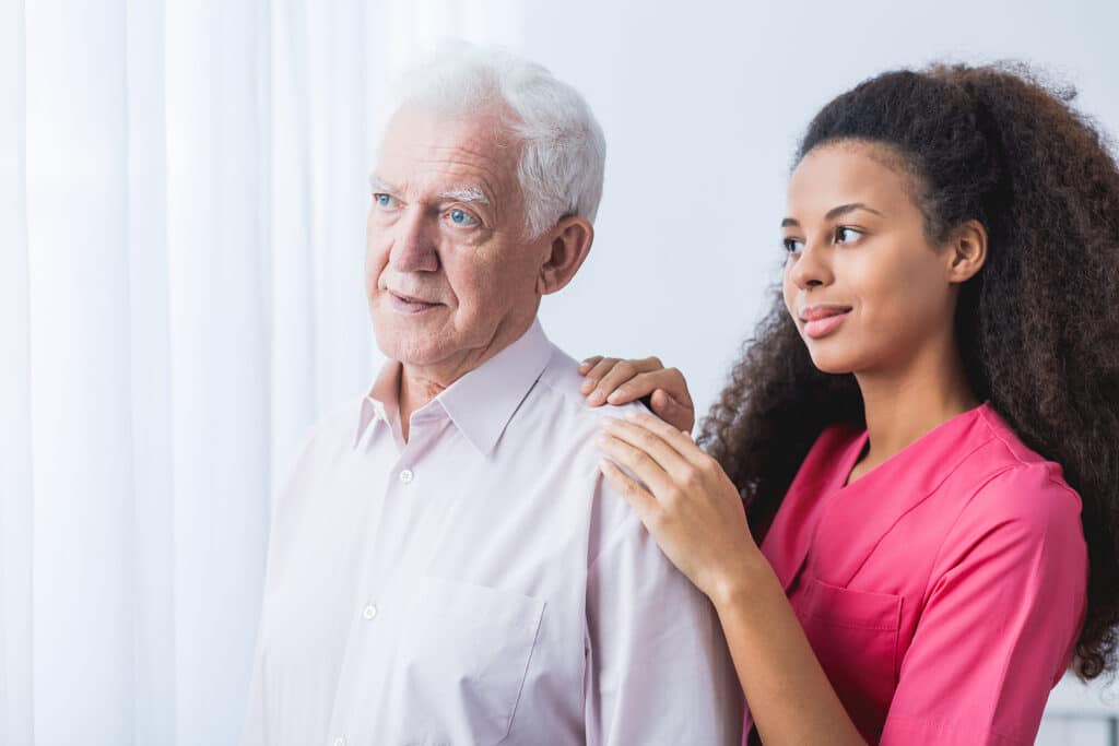 A woman is helping an older man to get up.