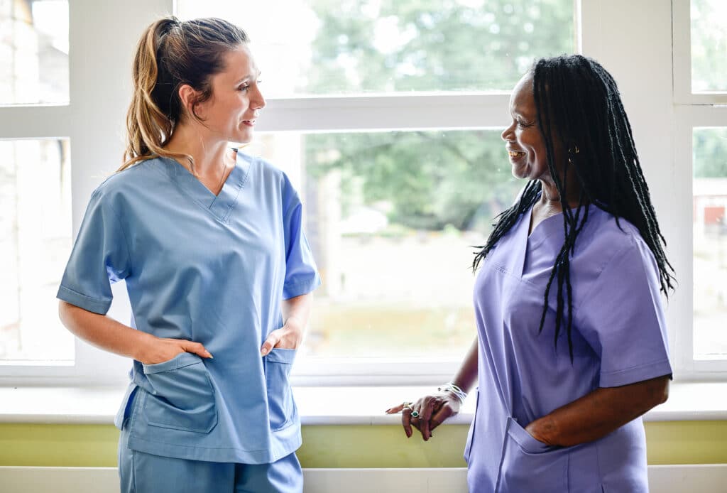 Two nurses talking to each other in a room.