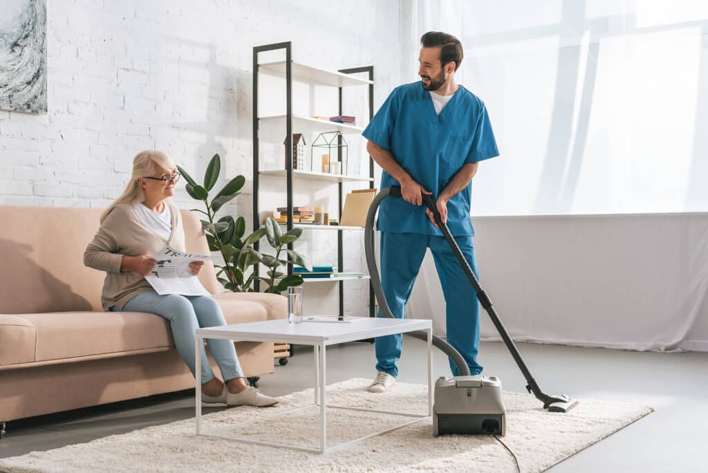 A man in blue scrubs is using a vacuum