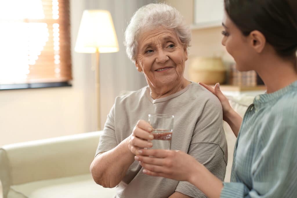 A woman holding a glass of water next to an older person.