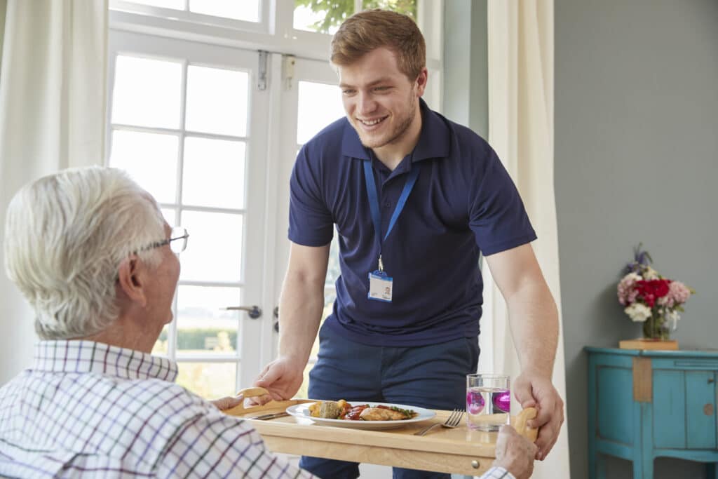 A man serving food to an elderly person.