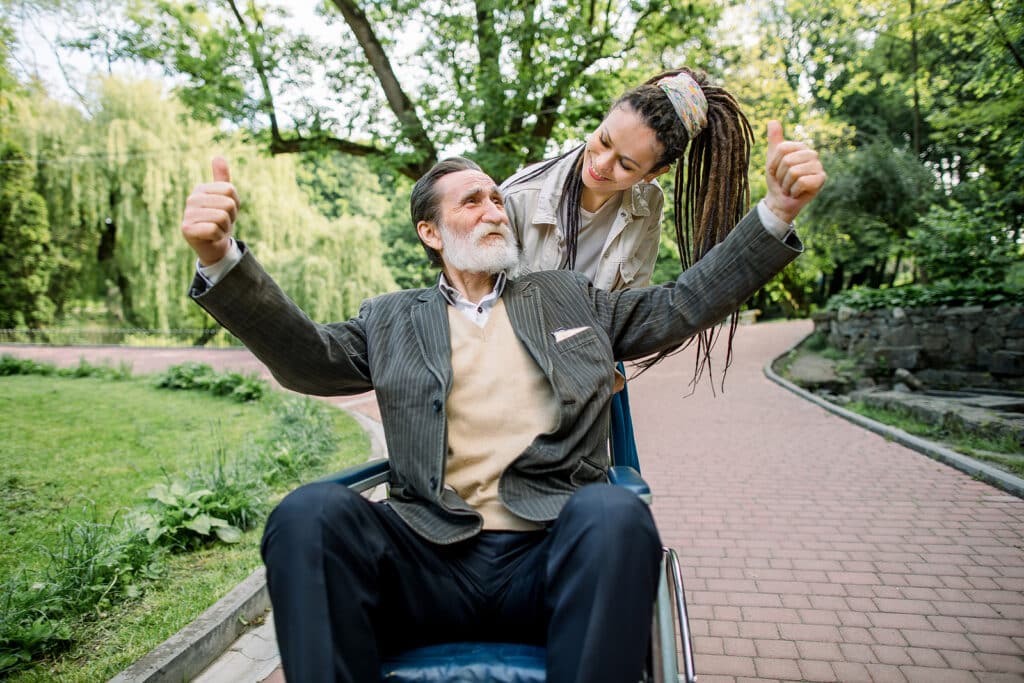 A woman is helping an older man in a wheelchair.